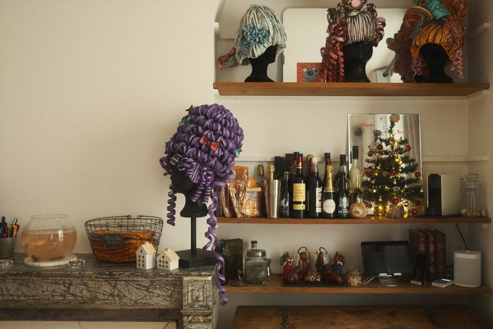 Paris apartment mantle of wigs, fish bowl, bottles, iPad playing Christmas music, mirror with reflection of decorated tree